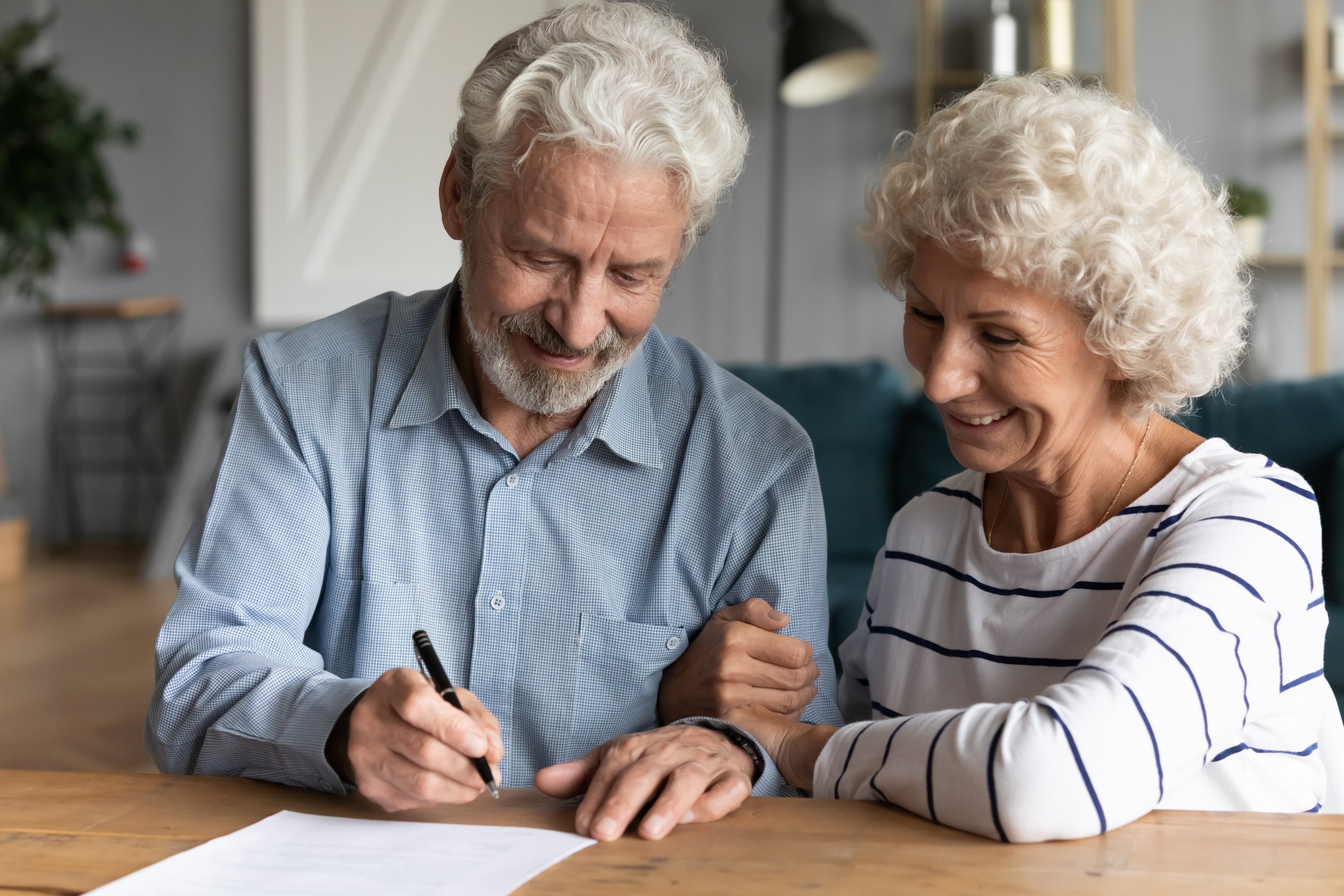 Elderly couple smiling while signing legal documents